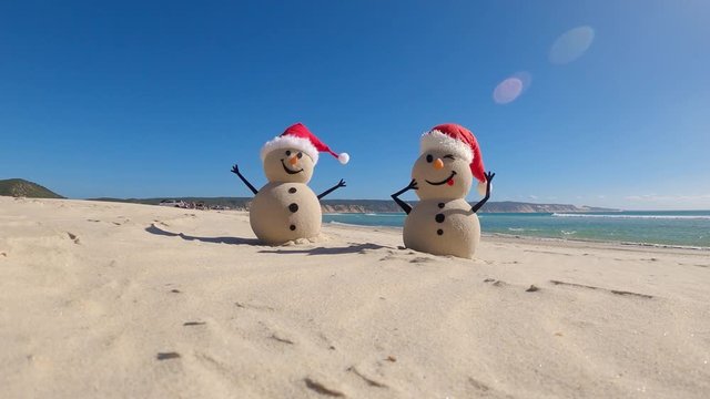 Two Sandy Christmas Snowmen are celebrating Christmas on a beautiful beach, zoom in