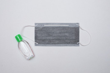 Coronavirus prevention using 3 ply surgical mask and hand sanitizer. Top view with white background.