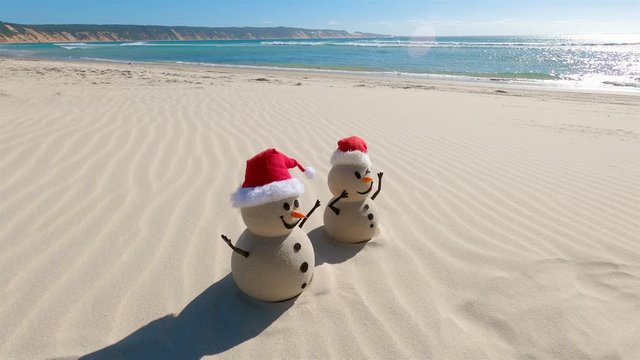 Two Sandy Christmas Snowmen are celebrating Christmas on a beautiful beach, zoom out