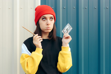 Millennial Hipster Girl Holding an Audio Tape Cassette and a Pencil