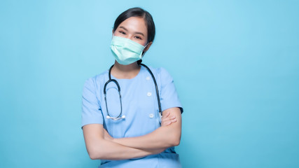 Portrait of young Asian beautiful nurse in blue uniform and wearing a surgical mask for protection from covid19 or disease with big smiled inside on copy space isolated on blue background