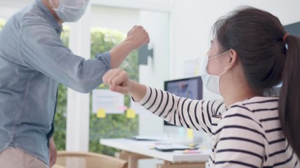 Elbow greeting to avoid the spread of coronavirus (COVID-19). Asian officer man and woamn wear face mask greeting with elbow bump at new normal office. Employee avoid touch for coronavirus prevention