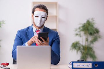 Male employee with mask in hipocrisy concept