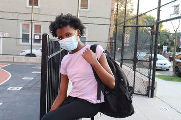 African American girl wearing mask and backback outdoors at school school playground