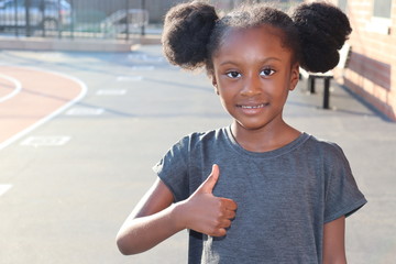 Girl smiling with thumbs up gesture outdoors
