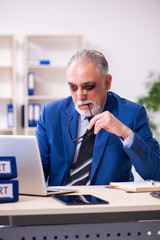 Old face injured employee sitting in the office