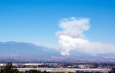 Fototapeta na wymiar Wildfire smoke emerges from near Banning in the Apple fire of August 2020 in southern California. The cities of Riverside and Moreno Valley are in the foreground