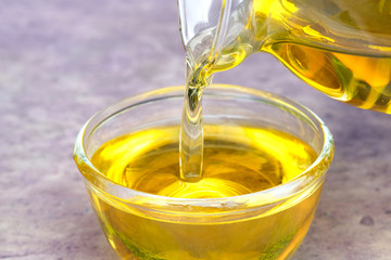 Pouring olive oil in the a glass bowl at stone kitchen and inside green garden view. Prepare for cooking concept. Healthcare and Beauty Concept.