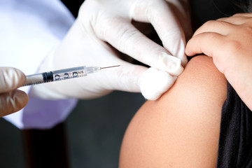 doctor's hand holds a syringe and a blue vaccine bottle at the hospital. Health and medical concepts.