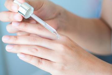 hands of a beautiful woman Dropping serum collagen moisturizer of face into hand soft light background. Protector skin Treatment facial essence oil, Vitamin C. Beauty and spa concept