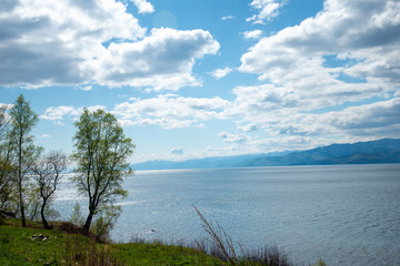 The coast of Lake Baikal on the Circum-Baikal Railway. Circum-Baikal railway tour in Siberia with trees, cliffs and mountains at coast. 
Baikal.
