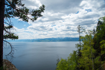 The coast of Lake Baikal on the Circum-Baikal Railway. Circum-Baikal railway tour in Siberia with trees, cliffs and mountains at coast. 
Baikal.

