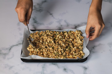 Closeup shot of a chef spreading an oat mixture onto a baking sheet
