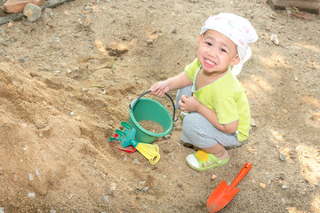 Thai baby boy palying on  pile of sand with toy and plastic fork