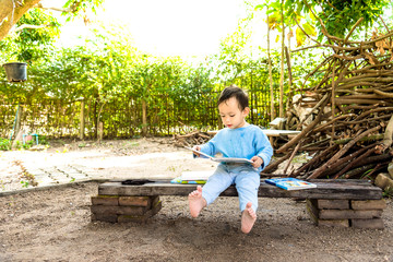Asian baby boy reading tale book alone