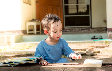 Asian baby boy reading tale book alone at outdoor