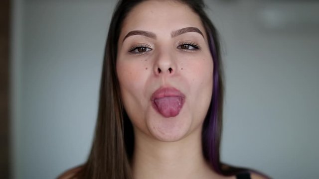 Young woman showing tongue. Pretty girl sticking tongue out with funny expression