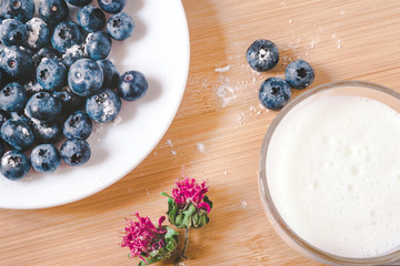 Concept of healthy food, morning Breakfast. Blueberries on a white plate, sprinkled with powdered sugar. There's a milkshake next to it.