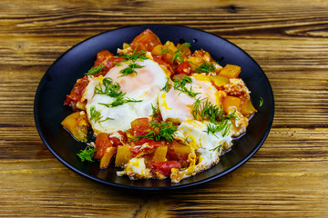 Homemade breakfast shakshuka - fried eggs, onion, bell pepper, tomatoes and dill on rustic wooden table. Jewish cuisine