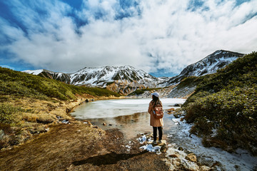 Asian woman is standing at swamp that is named Midorigaike in Tateyama-Kurobe alpine route or Japan...