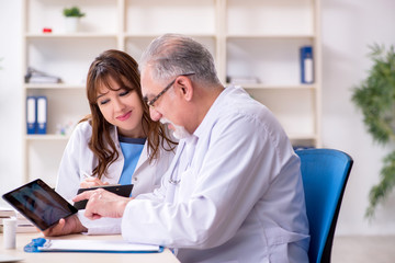 Old male doctor radiologist and his young female assistant in th