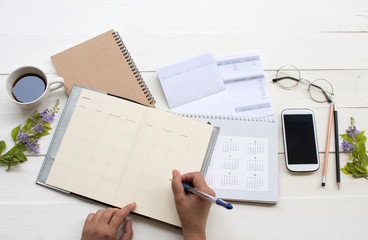hand of woman working with saving account passbook bank ,statement due expenses of credit card...