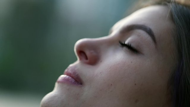 Young woman with eyes closed in meditation outside. Girl face opening eyes looking up to sky