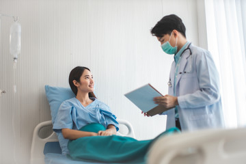 Medicine and health care concept.  Asian doctor is taking care patient woman in hospital.doctor or nurse wear protection mask checking and takecare infection people from covid-19 .