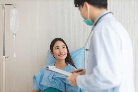 Medicine and health care concept.  Asian doctor is taking care patient woman in hospital.doctor or nurse wear protection mask checking and takecare infection people from covid-19 .