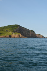 Cape or island on the blue sea background