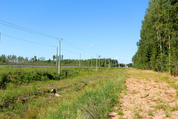 Fototapeta na wymiar railroad tracks in the countryside surrounded by forest under bright blue summer sky