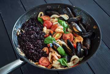 paella with black rice and seafoods