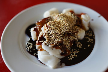 A plate of rice noodle roll with sweet sauce and chili paste also known as Chee Cheong Fun, Cantonese dish, Dim Sum meal.