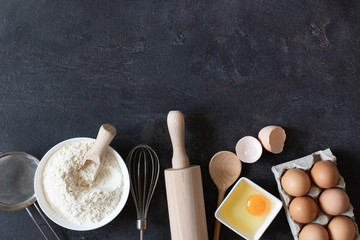 Ingredients and tools for dough preparation on black background top view.
