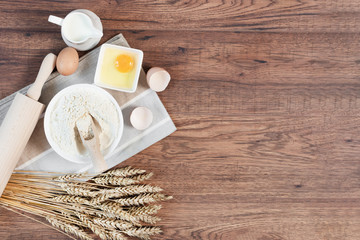 Ingredients and tools for dough preparation on wooden background top view.
