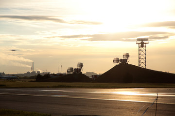Fototapeta na wymiar airport equipment on flying field - high board and radiolocators against dawning sun. Horizontal image