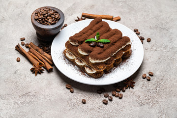 Classic tiramisu dessert on ceramic plate on concrete background