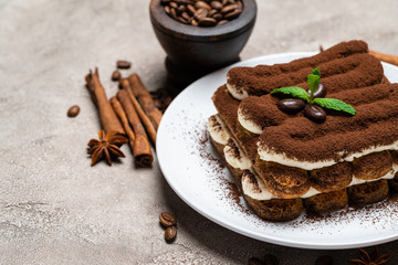 Classic tiramisu dessert on ceramic plate on concrete background