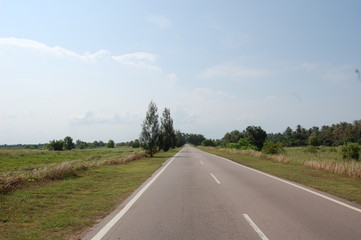 東南アジアのマレーシアの田舎にある草原の風景と青い空と真っすぐな道