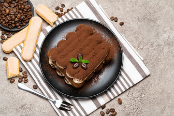 Classic tiramisu dessert and savoiardi cookies on ceramic plate on concrete background
