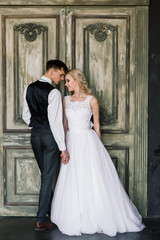 Fototapeta premium Cute wedding couple in the interior of a classic studio decorated. They kiss and hug each other.