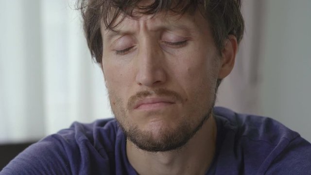 Closeup shot of a young man in mandatory quarantine. He stays in one room for two weeks. He did not shave for a long time, he is stressed and upset. Staying in quarantine concept. Concept of the