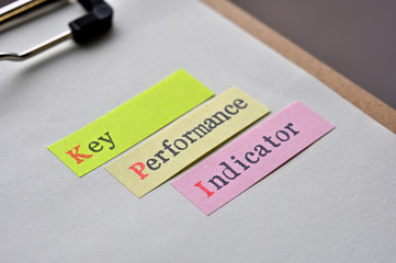 The words "KPI" written on sticky note with clipboard in diagonal angle.