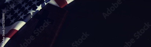 American flag and holy bible book on a mirror background. Symbol of the United States and religion. Bible and striped flag on a black background.
