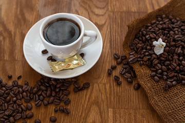 coffee cup on dark wood with roasted coffee beans, espresso with gift and white flower, Kaffee Tasse 