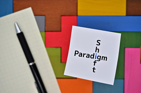 There is a piece of paper with the word "Paradigm Shift" on colored blocks.