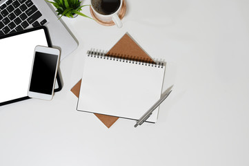 Office desk with computer and gadget device with empty notebook on simple workspace top view.