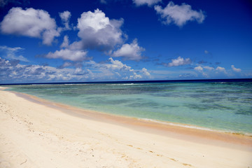 Fototapeta na wymiar Deserted sunny tropical sandy beach and blue sea with sky and clouds in Guam, Micronesia