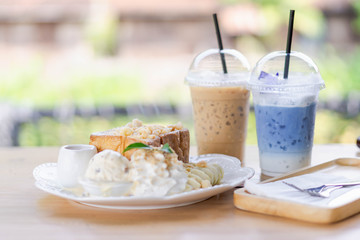 Honey toast dessert with ice coffee on wood table