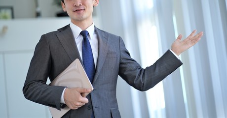 スーツを着て説明するアジア人男性